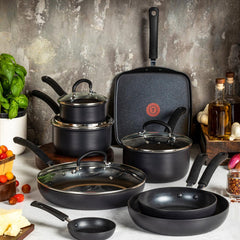 Black nonstick cookware set with pots, pans, griddle, and glass lids on dark kitchen counter
