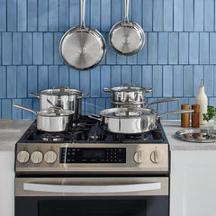 T-fal stainless steel cookware 12 piece set on gas range with blue tile backsplash in modern kitchen