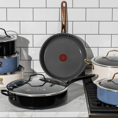A set of various cookware placed on a kitchen countertop. Includes pots and pans with lids, showcasing different styles and handles.