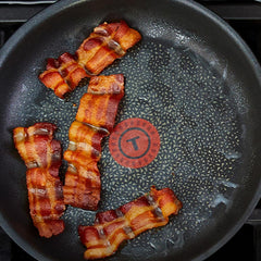 Four strips of cooked bacon in a nonstick frying pan with a red Thermo-Spot in the center