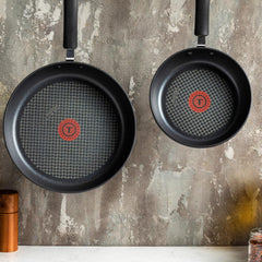 Two frying pans hanging on a kitchen wall