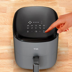 A hand operates the touch interface of a black T-fal Easy Fry Max air fryer