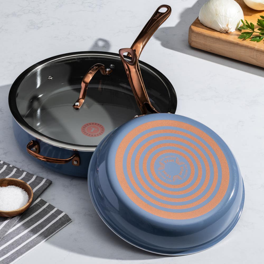 Two pans on a kitchen counter; one upright with black interior, one upside down showing red Thermospot. Ingredients nearby.