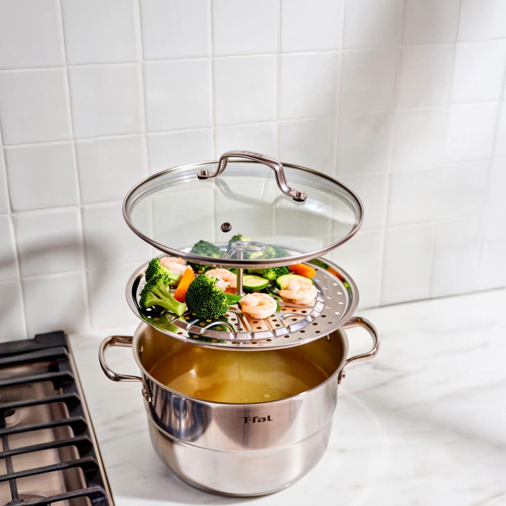 T-fal steamer pot on stove with shrimp and broccoli on insert tray, lid lifted open