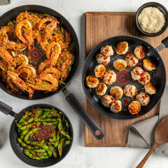 Three Ultimate Hard Anodized pans with different cooked dishes: shrimp, dumplings, and vegetables.