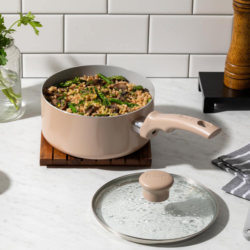 T-fal beige saucepan filled with rice and mushrooms beside a glass lid on a white countertop