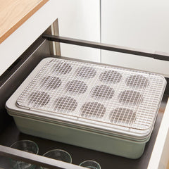 Stacked baking trays with cooling rack, inside an open kitchen drawer.