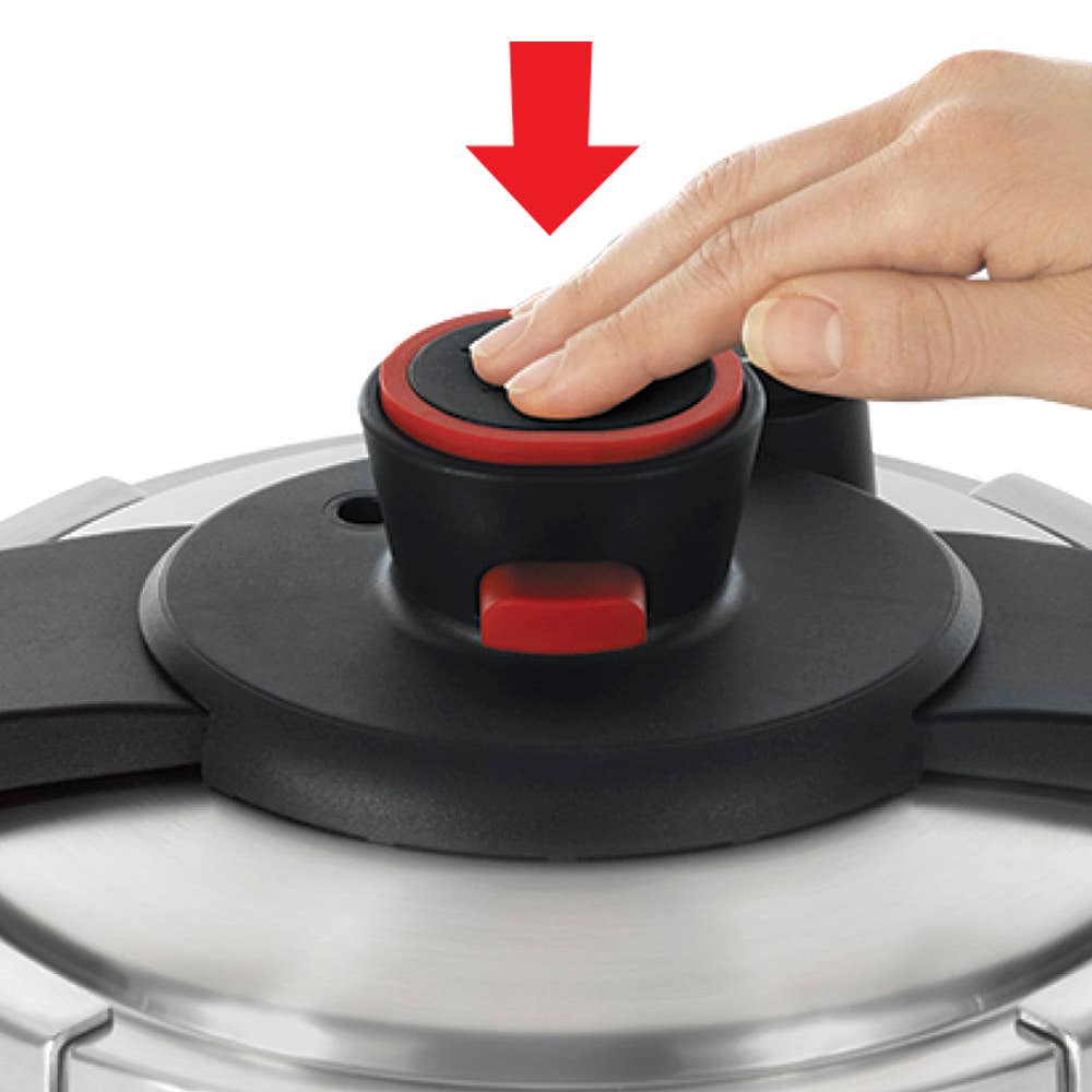 A hand presses down the red-buttoned locking mechanism on a pressure cooker lid, indicating the secure seal function.
