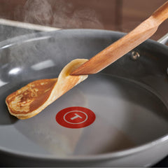 A spatula flipping a pancake in a skillet.