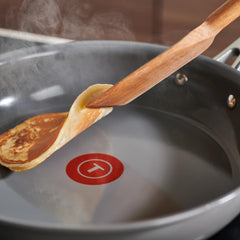 A spatula flipping a pancake in a skillet.