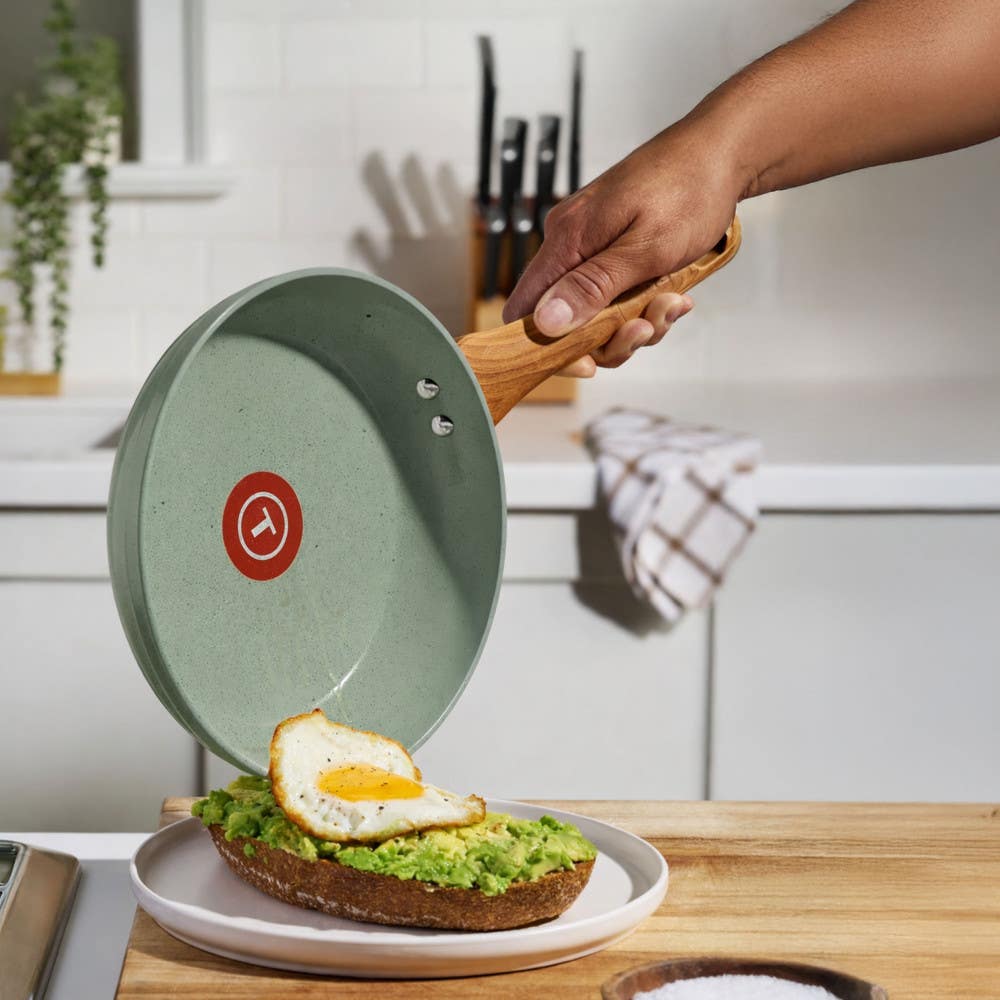 T-fal green ceramic frypan pouring fried egg onto avocado toast on a kitchen counter