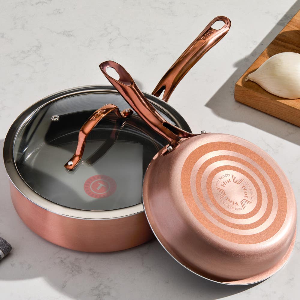 Two pans on a kitchen counter; one upright with black interior, one upside down showing red Thermospot. Ingredients nearby.