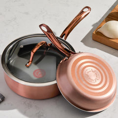 Two pans on a kitchen counter; one upright with black interior, one upside down showing red Thermospot. Ingredients nearby.