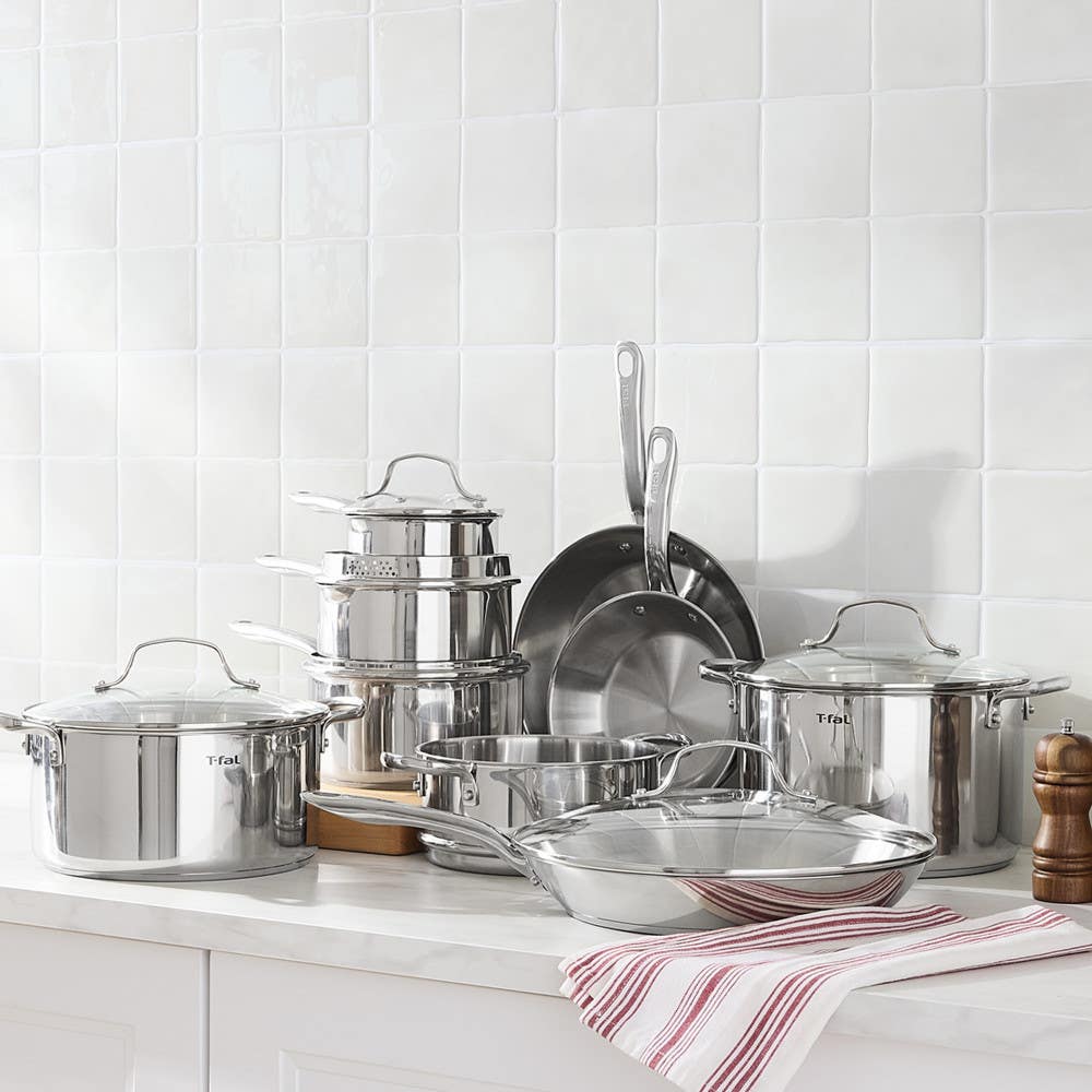 Stainless steel cookware set arranged on a white kitchen counter.