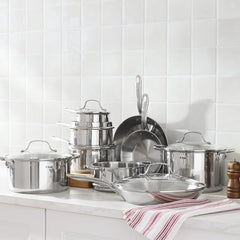 Stainless steel cookware set arranged on a white kitchen counter.