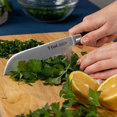 Chopping herbs with a T-fal knife, lemons nearby on cutting board.