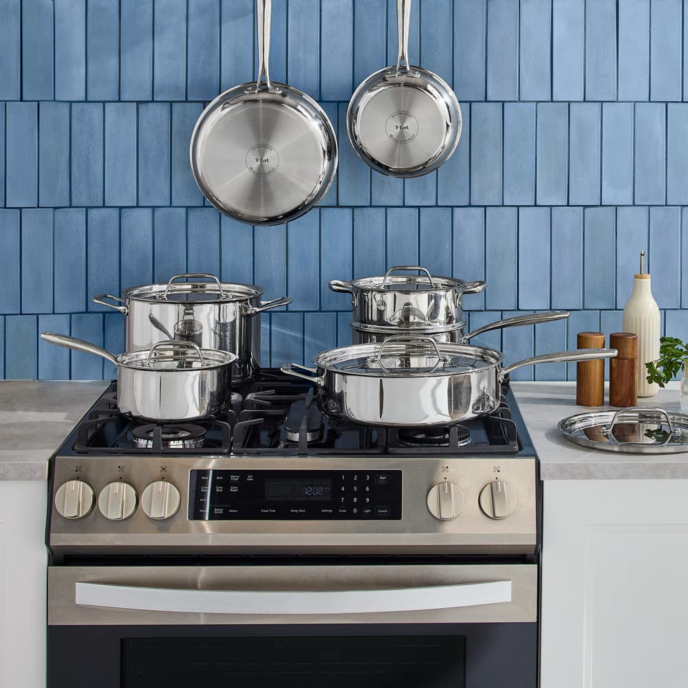 T-fal stainless steel cookware 12 piece set on gas range with blue tile backsplash in modern kitchen
