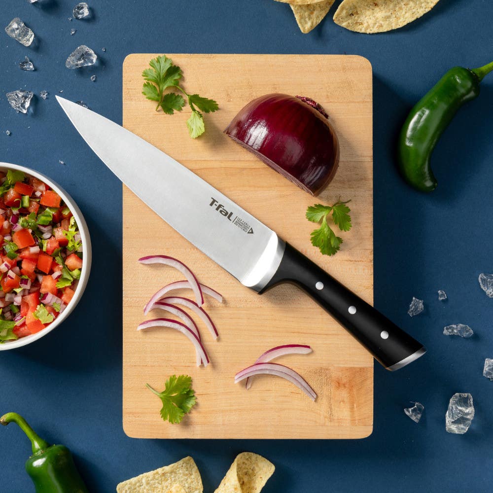 Cutting board with sliced onion and chef's knife, surrounded by food on blue background.