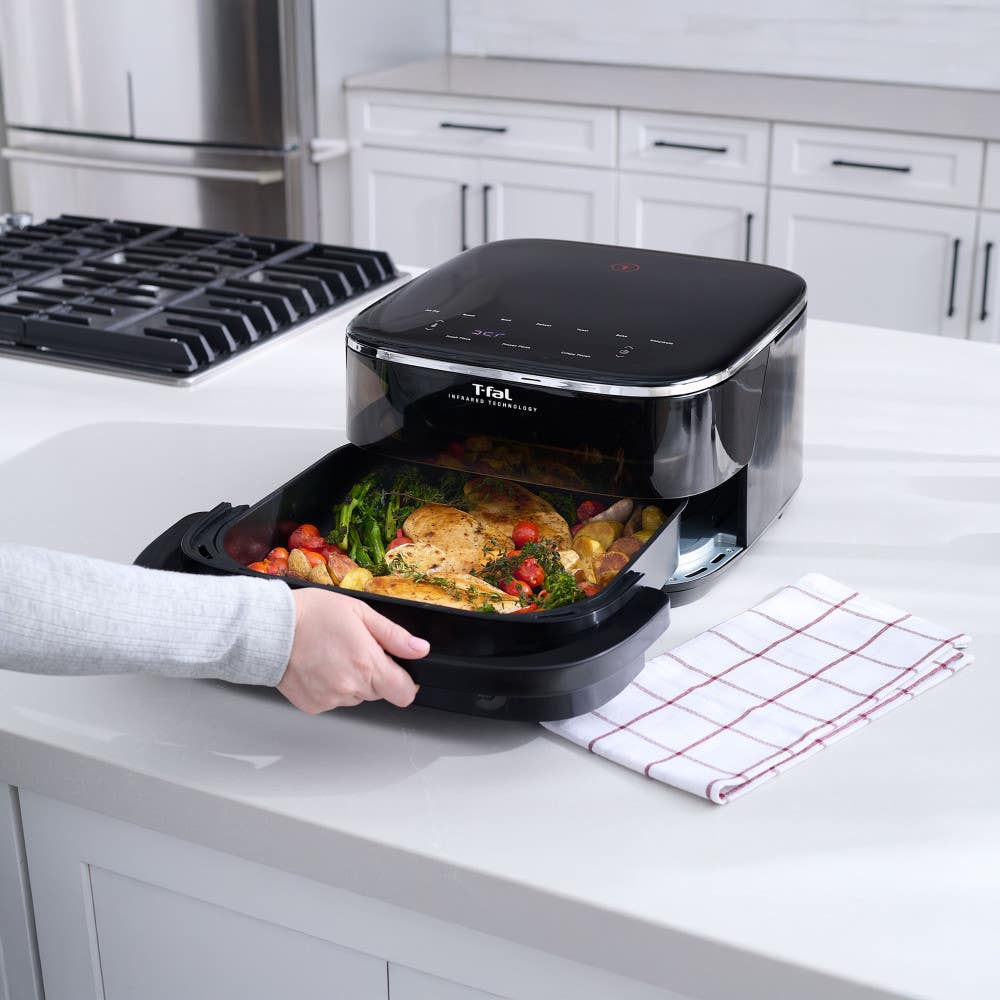 Infrared Surface XXL Air Fryer by T-fal, basket being pulled out to reveal cooked chicken with vegetables inside on a kitchen counter