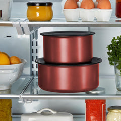 Stacked red pots with black lids in a refrigerator, surrounded by other food items