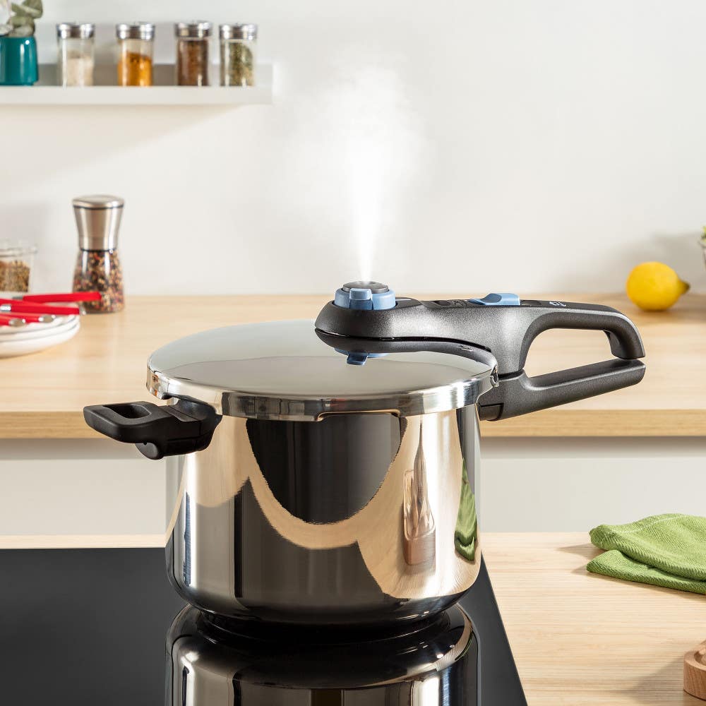 Pressure cooker releasing steam in bright kitchen with on wooden countertop