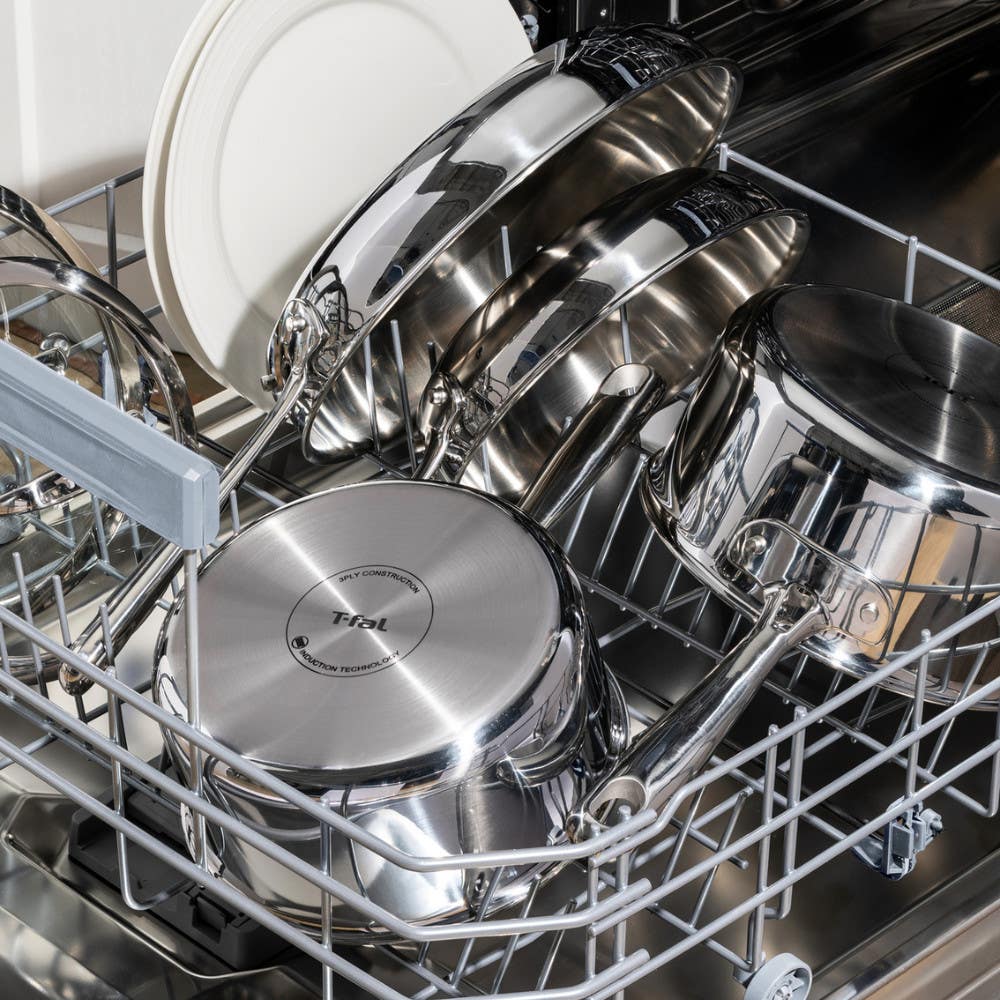 shiny stainless steel cookware and plates loaded in a dishwasher for cleaning