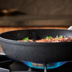 Stone Force Frying Pan on a gas stove with food and herbs.