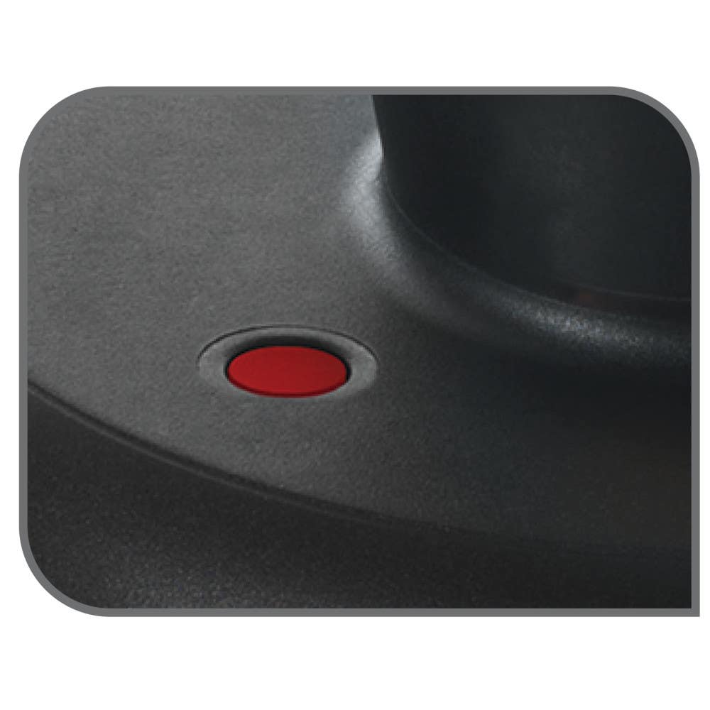 A close-up of a pressure cooker's safety valve showing a red button set against a dark surface, highlighting its secure design.