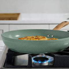 T-fal green ceramic frypan cooking a golden omelet on a gas stovetop with blue flame