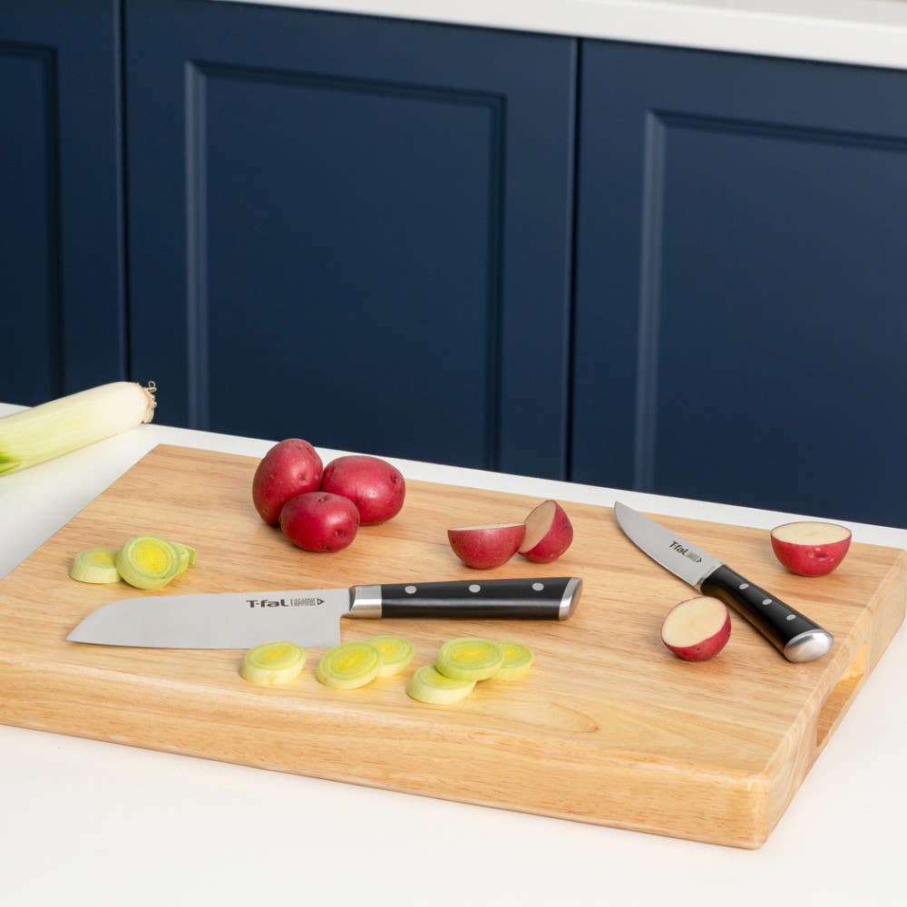Two T-fal knives on cutting board with potatoes and leeks.