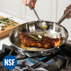 Person cooking a steak in a stainless steel pan on a stovetop, with an NSF logo visible