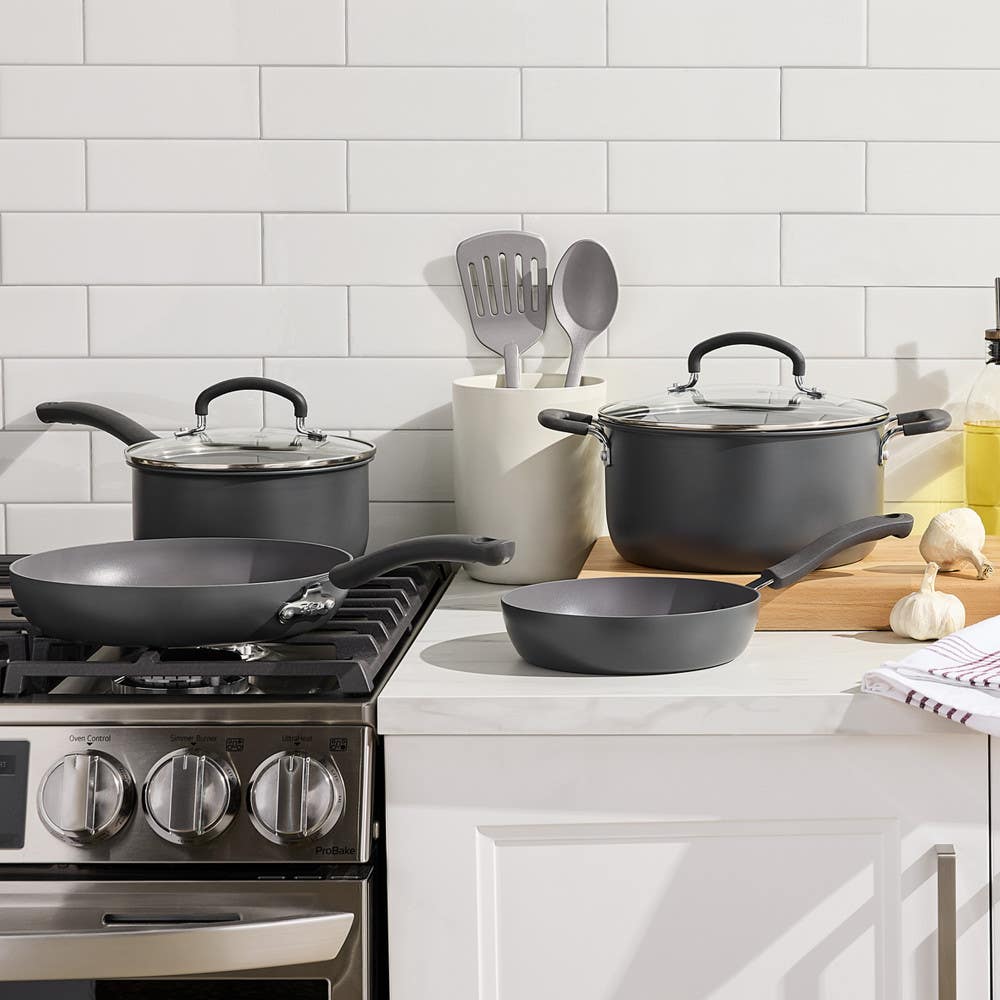 Set of ceramic cookware and utensils arranged on a kitchen stove and counter.