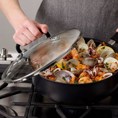 Person lifting lid off a jumbo cooker filled with seafood stewing on a stove.