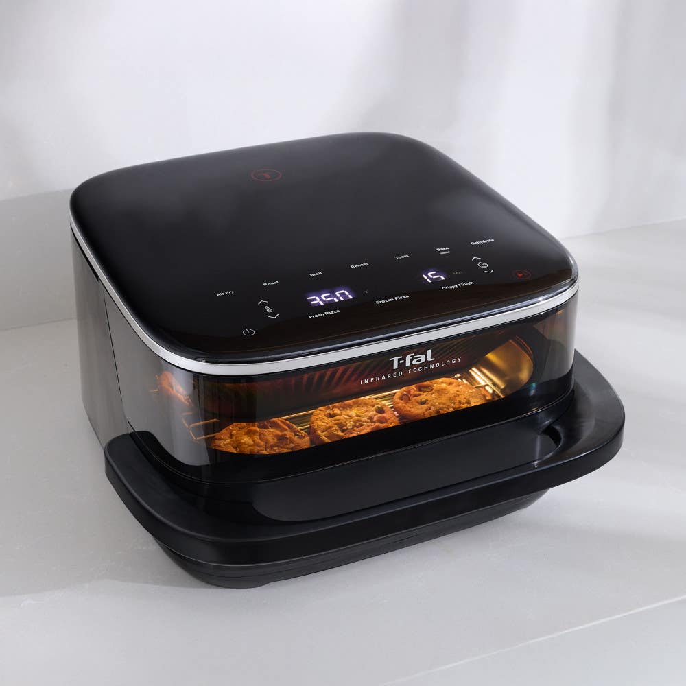 Infrared Surface XXL Air Fryer by T-fal, black appliance with digital controls, food cooking inside visible through the front window glowing warm orange.