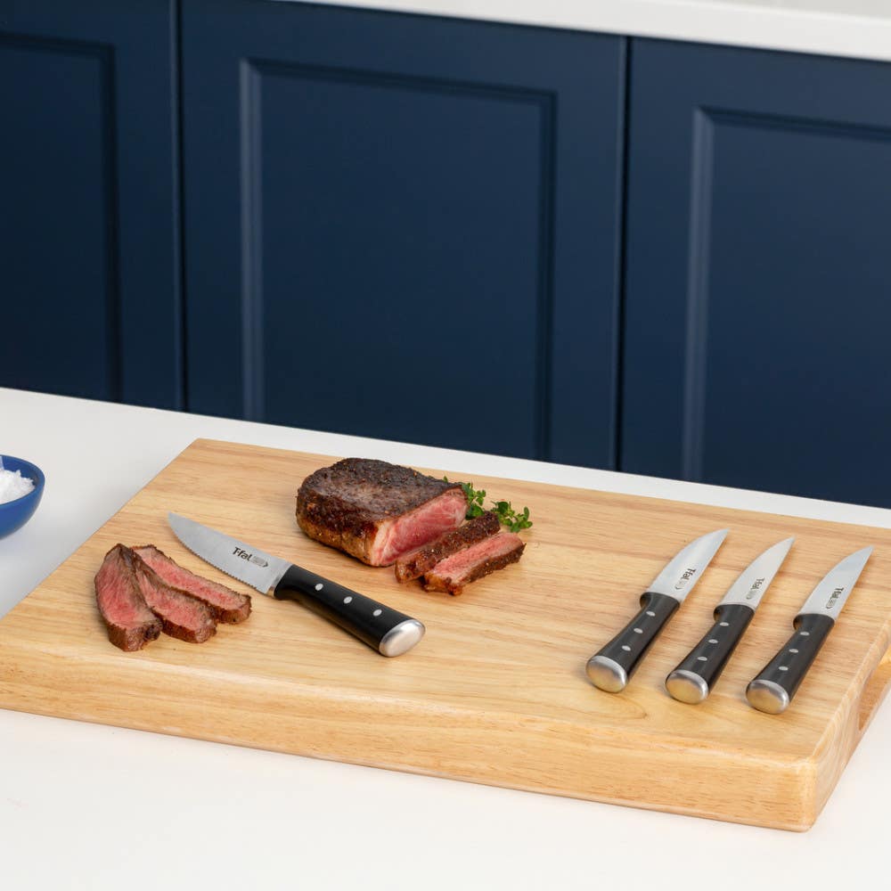 Sliced steak on cutting board with knives beside it.