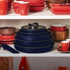 Stacked blue cookware among red and white dishware in a cabinet and a detachable handle