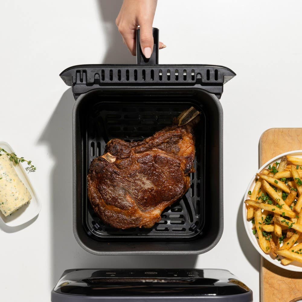 Overview of infrared air fryer showing a perfectly cooked steak in the basket, with a side of fries and dip nearby