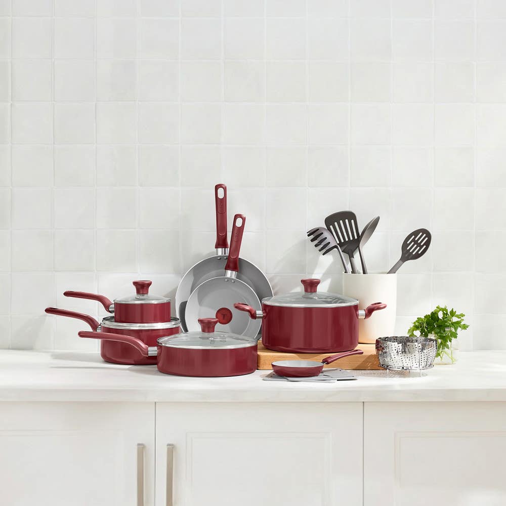 Red cookware set with frypans, stockpot, saucepan and steamer on kitchen countertop