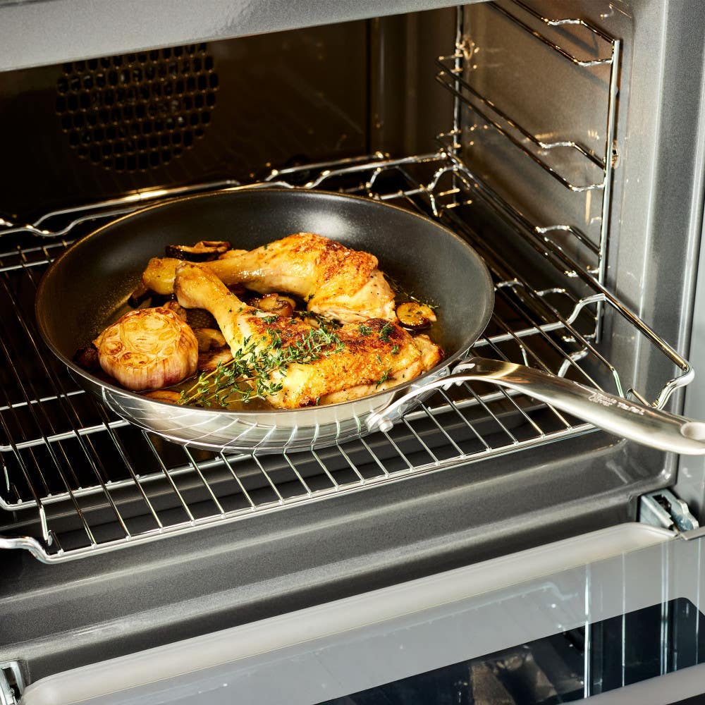 Roasted chicken and garlic cooking in stainless nonstick frypan inside oven