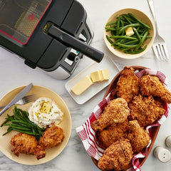 T-fal deep fryer on a kitchen counter beside a meal of crispy fried chicken, mashed potatoes, green beans, and butter