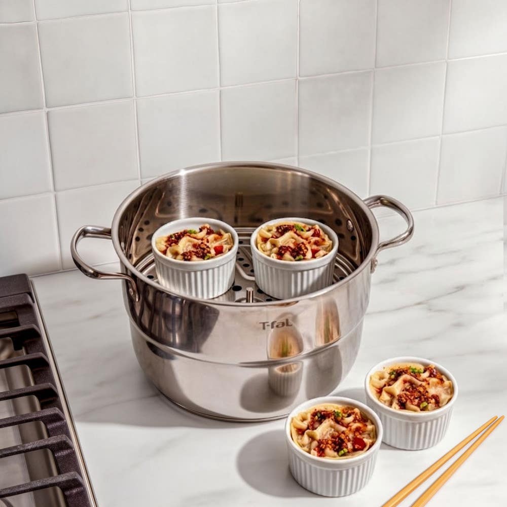 T-fal stainless steamer pot with ramekins of food on insert tray, chopsticks alongside