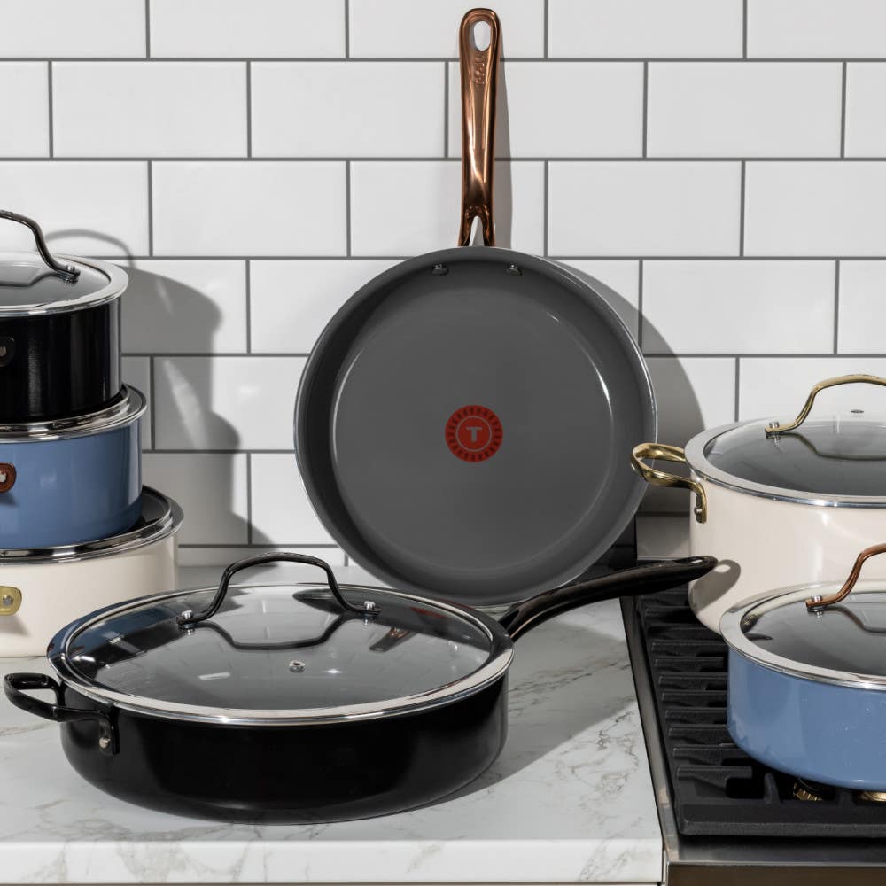 A set of various cookware placed on a kitchen countertop. Includes pots and pans with lids, showcasing different styles and handles.