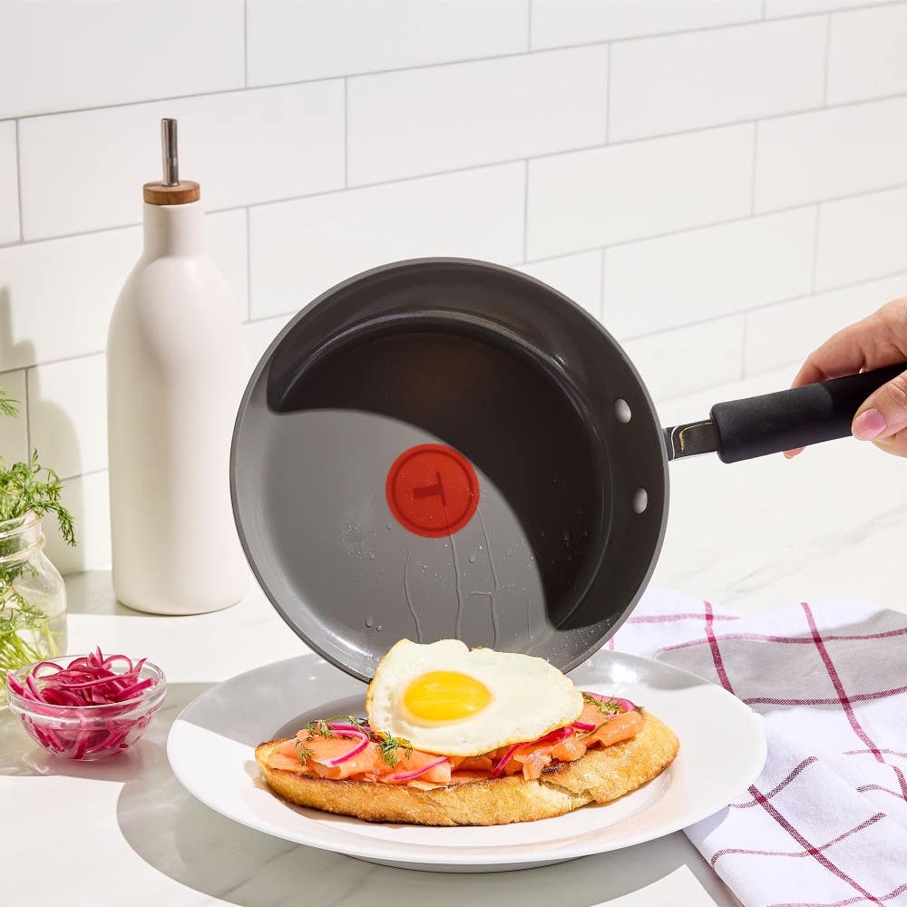 Ceramic frying pan shown preparing a fried egg on toast with toppings.