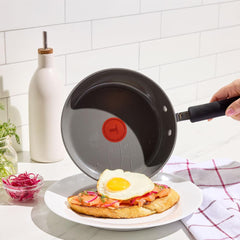 Ceramic frying pan shown preparing a fried egg on toast with toppings.