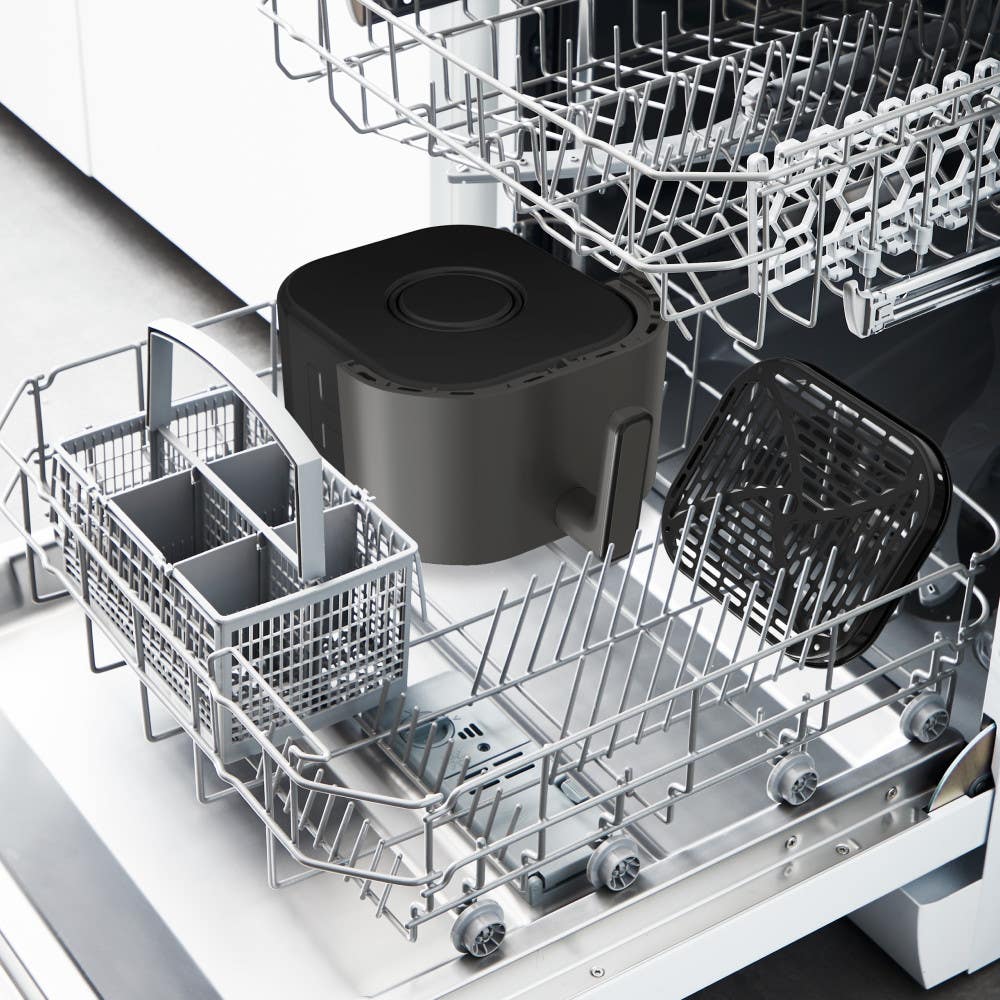 Dishwasher interior with black air fryer basket and tray on racks, indicating dishwasher compatibility.