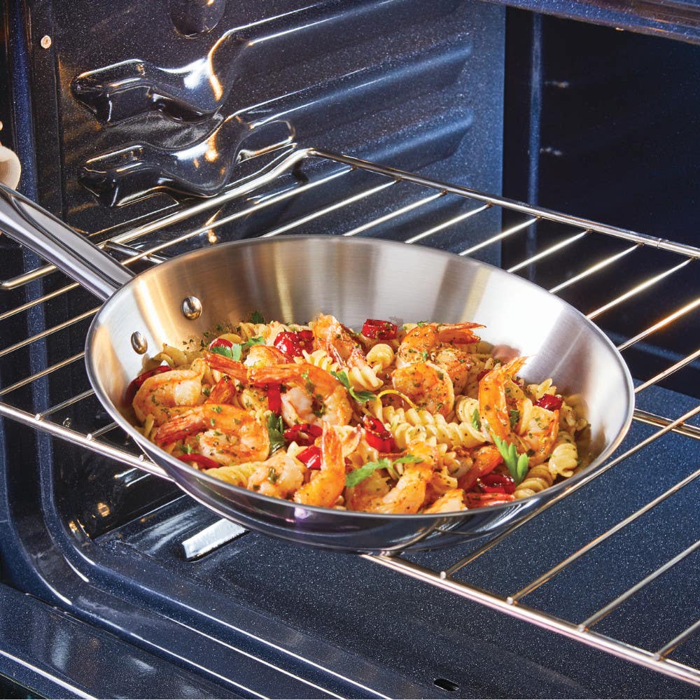 Stainless steel pan with pasta, shrimp, and vegetables on oven rack.