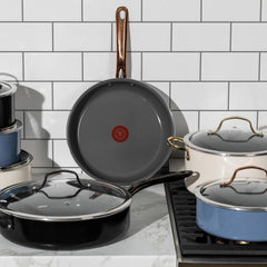 A set of various cookware placed on a kitchen countertop. Includes pots and pans with lids, showcasing different styles and handles.