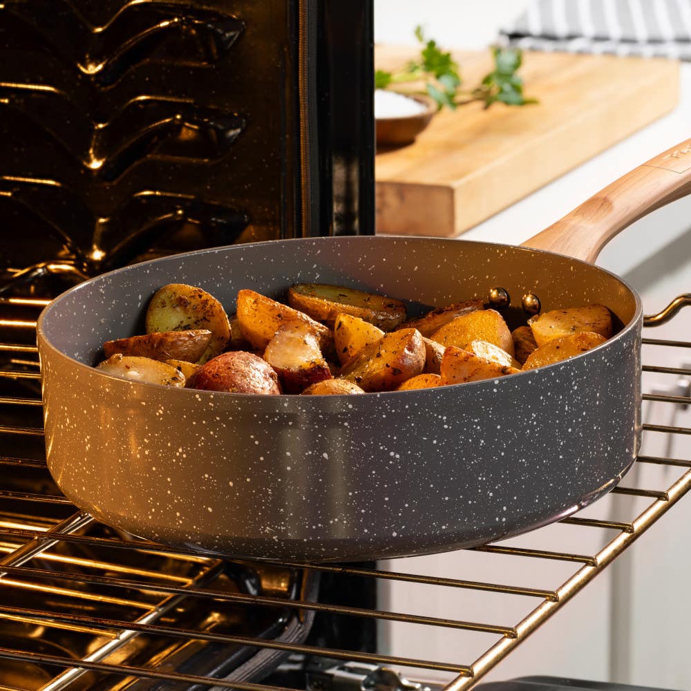 Gray ceramic jumbo cooker with roasted potatoes, placed in an oven on the oven rack