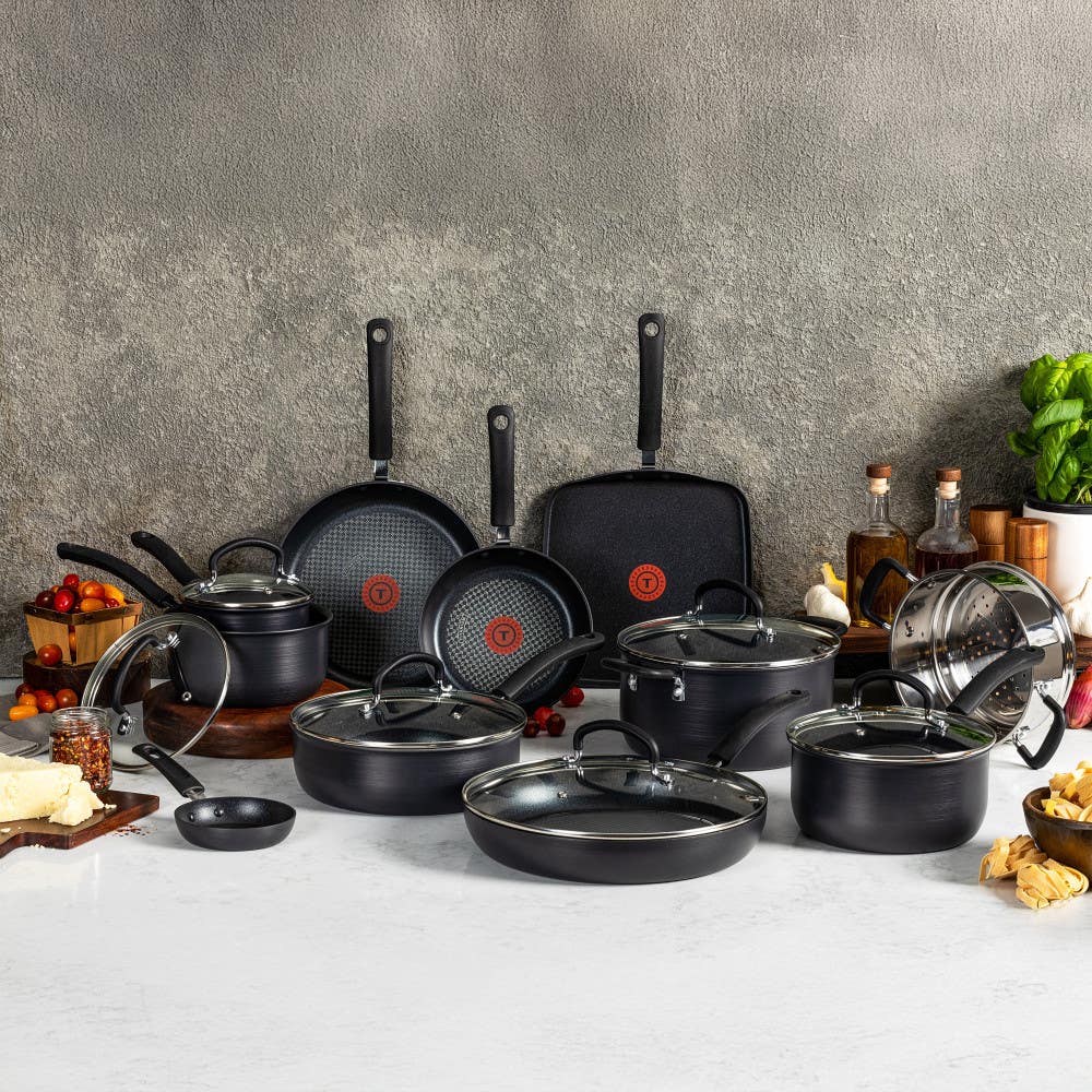 Black nonstick cookware set with pots, frying pans, griddle, glass lids on marble counter