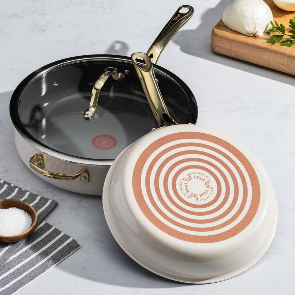 Two pans on a kitchen counter; one upright with black interior, one upside down showing red Thermospot. Ingredients nearby.